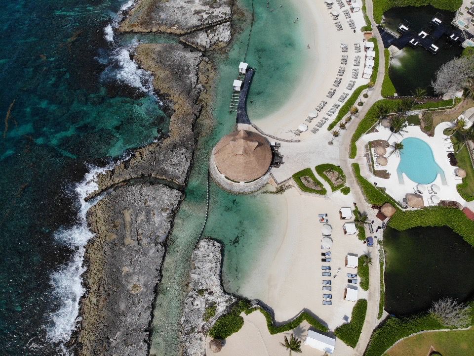 Aerial view of submerged coastal reef protection structures in turquoise Caribbean water alongside a resort beach